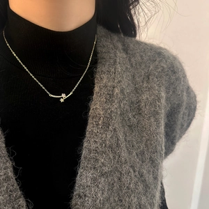 Detail of star-shaped zircon pendant necklace on grey mohair cardigan over black turtleneck