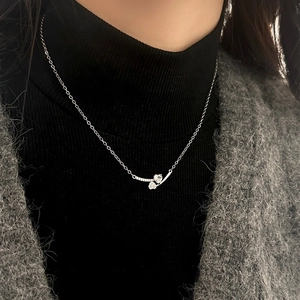 Detailed view of heart zircon pendant with silver chain on black sweater outfit