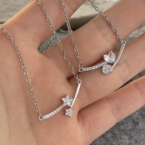 Macro shot of silver zircon star and heart pendant necklaces with fine link chain details