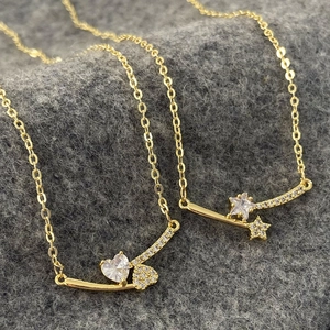 Detail of gold star and heart necklaces with sparkling zircon stones on grey background
