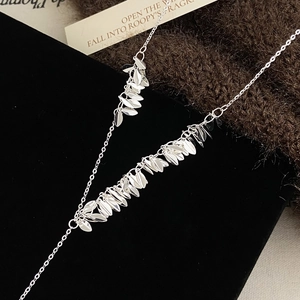 Silver leaf tassel necklace with polished metallic finish on elegant knit fabric background
