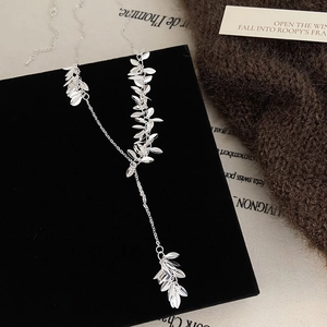 Detailed view of silver leaf tassel Y-shaped necklace on black velvet display board