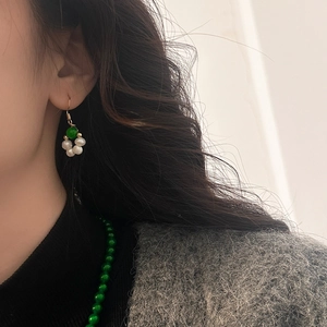 Gros plan sur une boucle d'oreille en perle verte et perles blanches sur un mannequin