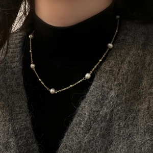 Elegant gold-tone freshwater pearl necklace on model wearing a black turtleneck sweater