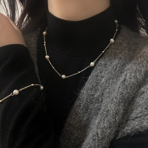 Elegant freshwater pearl necklace with gold chain worn on a black sweater for women