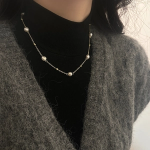 Elegant freshwater pearl necklace with gold beads on a model against a dark background
