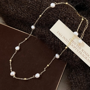 Detail of baroque pearl necklace with gold clasp and extension chain on fabric