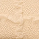 Macro shot of cream-colored pleated fabric with a textured popcorn seam detail