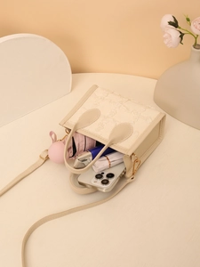 Detail view of beige floral textured bag showing interior space for phone and cosmetics
