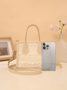 Detail of cream pleated ruffle handbag with leather strap and smartphone for size reference
