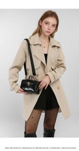 Close-up of glossy black box bag with golden dual zippers and wide detachable strap