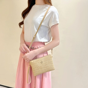 Sac bandoulière minimaliste en paille tressée beige avec une fine bandoulière en cuir