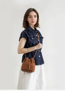Brown drawstring bucket bag with corduroy texture and leather trim on model