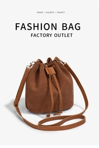 Detail of dark brown corduroy drawstring bucket bag with gold metal eyelets and strap