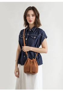Detail of brown corduroy bucket bag featuring leather base and drawstring closure