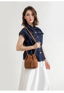 Detailed texture of brown corduroy bucket bag with drawstring and leather strap