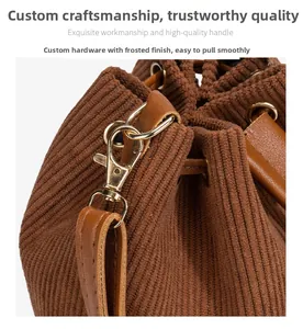 Detail of brown corduroy bucket bag showing leather handle and gold hardware clip