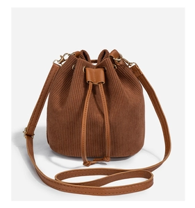 Close-up of brown corduroy bucket bag texture with PU drawstring and gold hardware