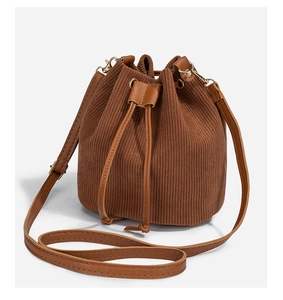 Detail of brown corduroy bucket bag showing texture, leather drawstring, and gold hardware