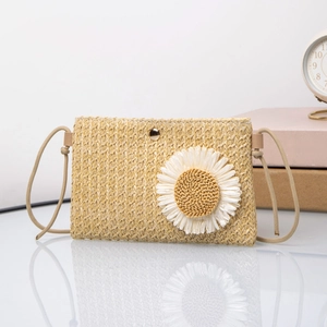 Detail of hand-woven straw crossbody bag with large white daisy and gold magnetic clasp