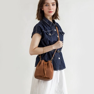 Modern brown corduroy bucket bag with leather trim shown on a model in a casual outfit