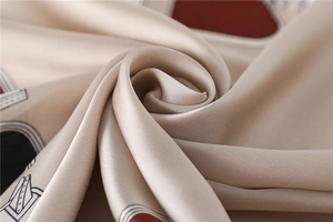 Vue macro d'un foulard en satin champagne montrant le tissu fin et les lignes géométriques