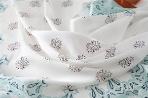 Makroaufnahme des Paisley-Musters auf weißem und mintgrünem Seidensatin-Stoff