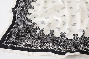 Nahaufnahme des Paisley-Seidenschals mit glatter Textur und elegantem schwarz-weißem Rand