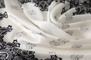 Makroaufnahme von Satin-Stoff mit Paisley-Muster zeigt seidige Textur in Cremeweiß