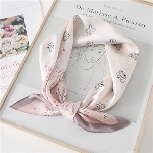 Eleganter Paisley-Seidenschal in Rosa und Grau, drapiert auf einem Kunstbuch
