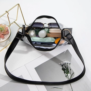 Minimalist transparent PVC underarm bag with black trim and lifestyle essentials inside