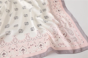 Detailansicht des cremefarbenen Seidenschals mit elegantem rosa Paisley-Muster und Glanz