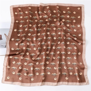 Detailed flat lay of a silk satin square scarf featuring cartoon dinosaur patterns
