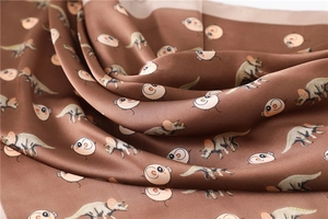 Detail of silk-like satin fabric with cute cartoon triceratops and animal patterns