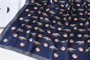 Detail of silk-like dark blue square scarf with cartoon dragon and pig prints
