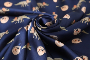 Macro detail of silky navy scarf with cartoon dinosaur prints showing smooth texture