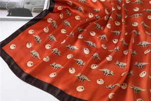 Satin scarf detail with triceratops print and dark brown border on caramel background
