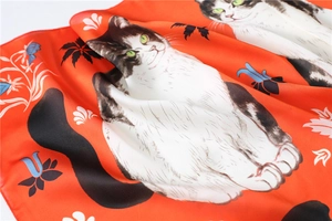 Detail van zijden sjaal met oranje kattenprint en blauwe bloemenpatronen