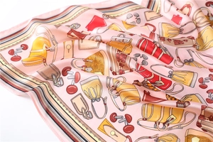 Detailed view of vintage handbag prints and satin texture on a pink silk-feel scarf