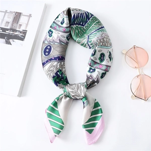 Dettaglio di un foulard satinato con foglie tropicali e righe geometriche e occhiali
