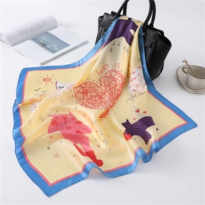 Detail van gele zijden sjaal met kattenpatroon gedrapeerd over een zwarte lederen tas