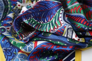 Dettaglio ravvicinato dei motivi paisley bohémien e dei colori vivaci sul foulard in seta