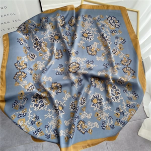 Macro shot of elegant floral silk scarf with vintage pattern on marble and gold tray