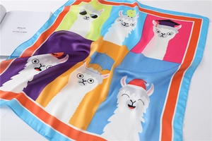 Detailopname van een zijden sjaal met kleurrijke alpaca-motieven en kunsttijdschrift