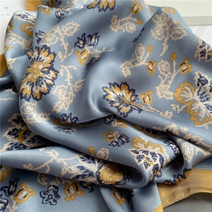 Detailed macro shot of vintage blue floral silk scarf with elegant yellow borders