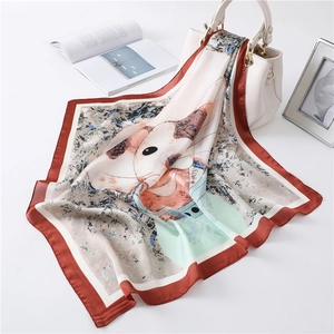 Detail van een zijden sjaal met kattenprint elegant gedrapeerd over een witte handtas
