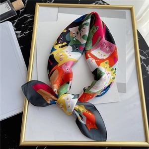 Detail van zijden sjaal met cartoon kattenprint geknoopt in een strik op marmer