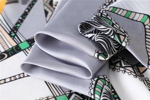 Close-up of geometric pattern silk square scarf with luxury satin finish and grey texture