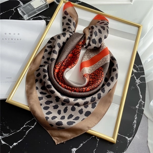Satin neck scarf featuring leopard print and orange color block on black marble surface