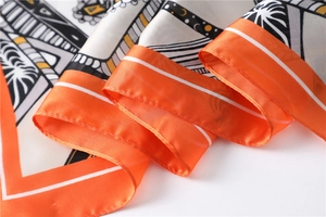 Detail of orange silk square scarf with geometric patterns and smooth rolled edges